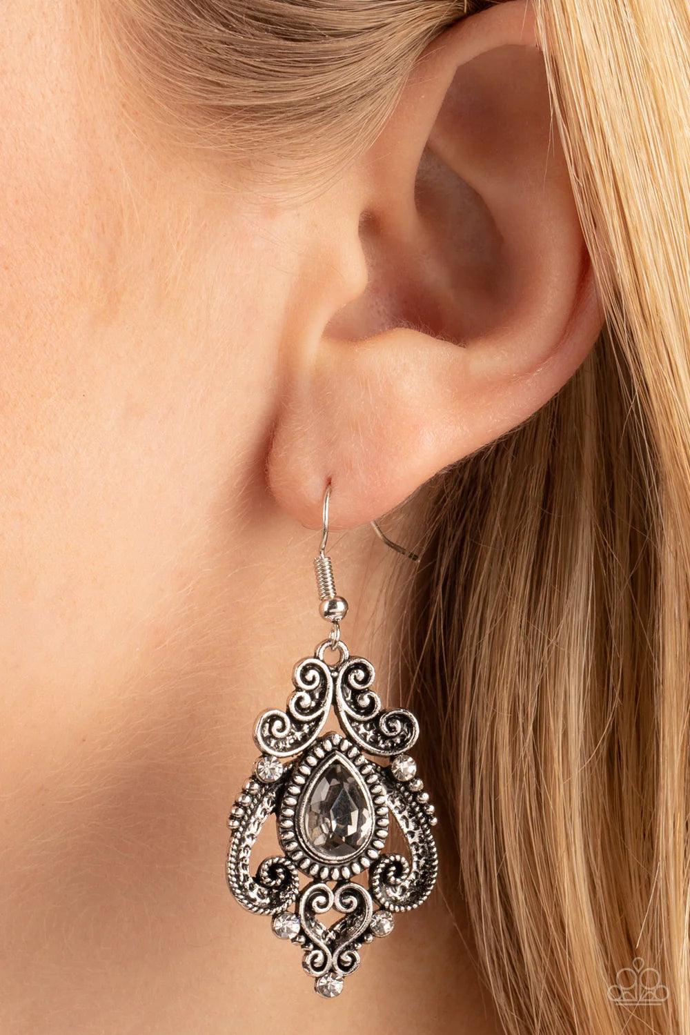 Paparazzi Accessories Palace Perfection - Silver Dotted with hints of glassy white rhinestones, studded and antiqued silver bars whirl into a regal heart shaped motif around a smoky teardrop center for a romantic finish. Earring attaches to a standard fis