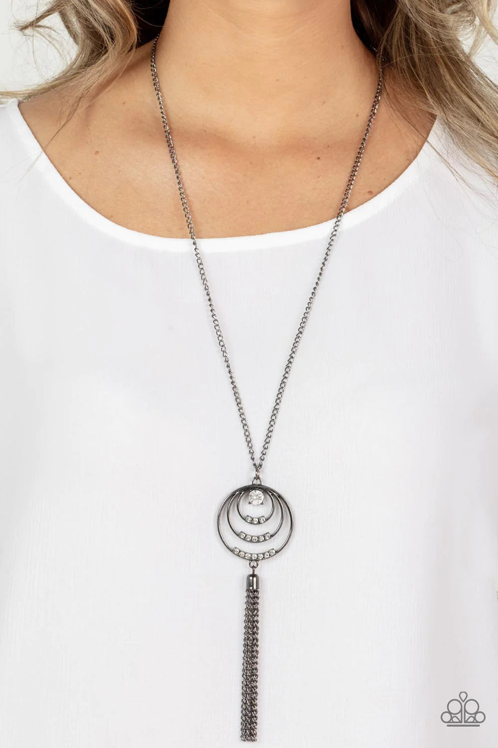 Paparazzi Accessories Spiraling Sparkle - Black Embellished with rows of white rhinestones, concentric gunmetal hoops connect into a single pendant at the bottom of a gunmetal chain. A glistening gunmetal chain tassel swings from the bottom of the display