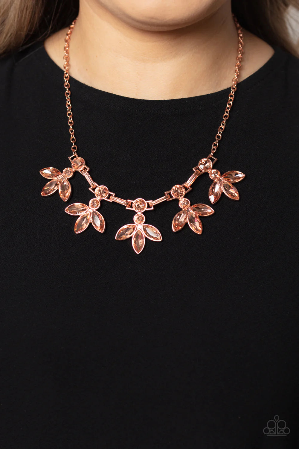 Paparazzi Accessories Dauntlessly Debonair - Copper Featuring warm marquise style cuts, oversized peachy gems fan out from an interconnected, circular peachy rhinestone display. Separating the warm florals, airy shiny copper ovals, stamped with a dot moti