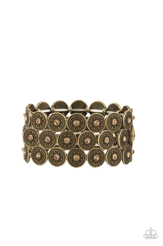 Paparazzi Accessories Forgotten Treasure - Brass Dotted with dainty golden topaz rhinestone centers, studded brass discs haphazardly stack into trios that have been threaded along stretchy bands around the wrist for a whimsical finish. Sold as one individ