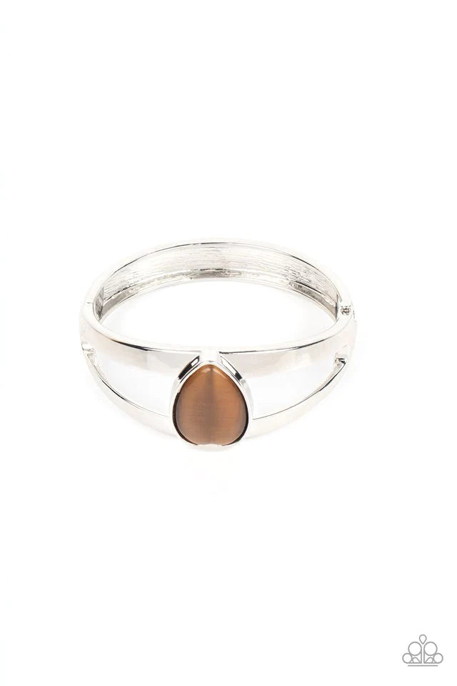 Paparazzi Accessories Enhanced Enchantment - Brown Encased in a sleek silver fitting, an oversized brown cat's eye teardrop stone is pressed into the center of a layered bangle-like bracelet for an enchanting fashion. Features a hinged closure. Sold as on