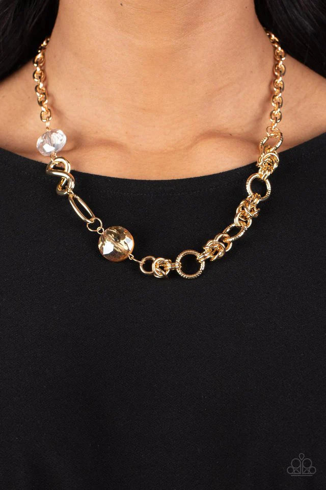 Paparazzi Accessories Celestially Celtic - Gold Thick links of gold twist into Celtic knot-like details, linking together with textured gold hoops along the collar. A pair of faceted, saucer-shaped crystal beads, dipped in a reflective gold coating and bo
