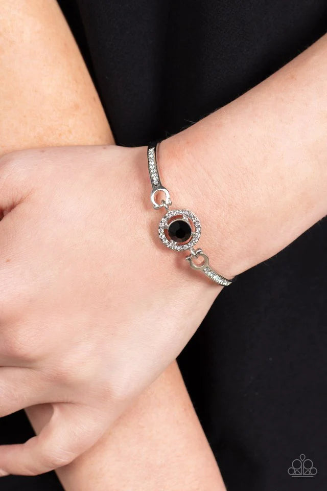 Paparazzi Accessories Focused and Fabulous - Black A brilliant black rhinestone sparkles inside a circular frame of dainty white rhinestones. Curved silver bars adorned with a row of rhinestones connect on each side of the frame, wrapping around the wrist