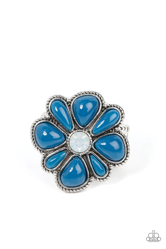 Paparazzi Accessories Meadow Mystique - Blue Featuring asymmetrical cuts, glassy Mykonos Blue beads bloom from an opal white rhinestone center atop a studded silver backdrop for a colorful floral fashion. Features a stretchy band for a flexible fit. Sold