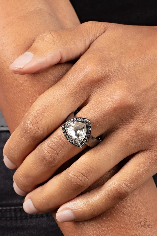 Paparazzi Accessories Tour De Timeless - Black An oversized trilliant cut white rhinestone encased in a sparkling rhinestone-encrusted gunmetal frame steals the spotlight and creates an eye-catching stunner atop the finger. Fea Jewelry