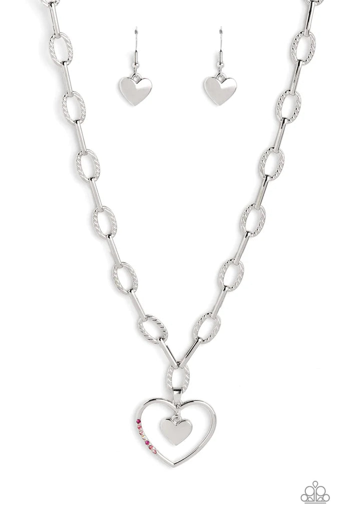 Paparazzi Accessories Refulgent Romance - Pink Textured ovals and elongated silver links lead the eye down to an oversized, airy, silver heart frame. Encrusted along one of the curves of the silver heart, dainty rhinestones in shades of pink, including fu