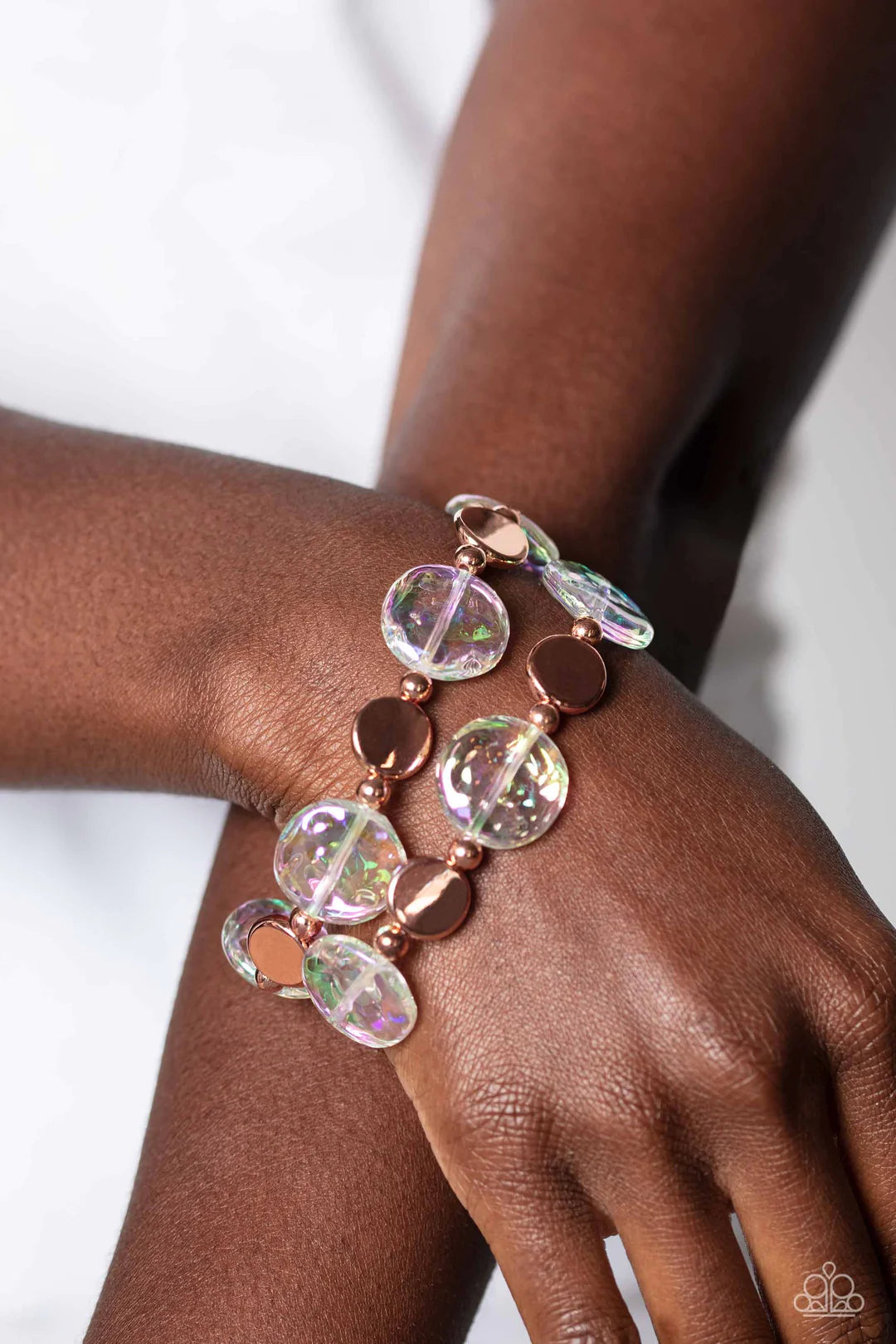 Paparazzi Accessories Discus Throw - Copper Shiny copper discs, studs, and asymmetrical clear discs featuring an iridescent shimmer coalesce around the wrist on elastic stretchy bands for an attention-grabbing shimmer. Due to its prismatic palette, color
