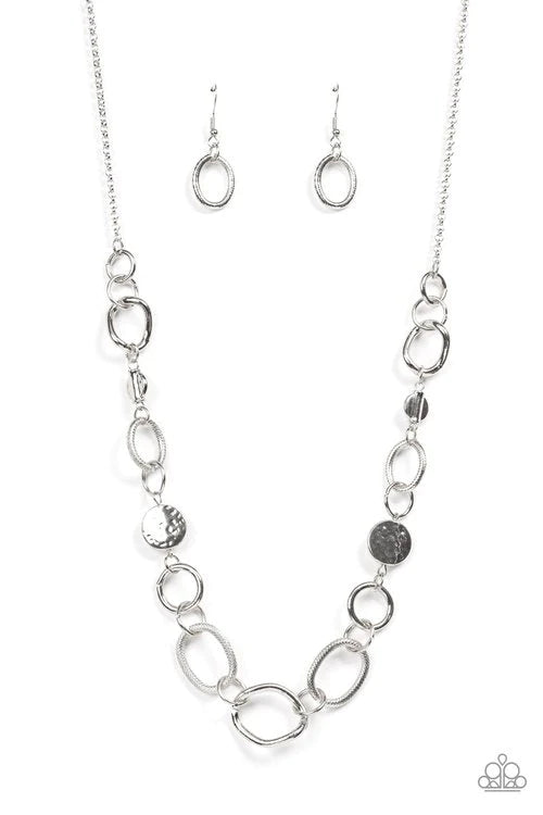 Paparazzi Accessories Industrial Intentions - Silver A mismatched assortment of hammered silver discs, textured silver links, shiny silver rings, and asymmetrical silver links boldly interlock below the collar for a gritty fashion. Features an adjustable