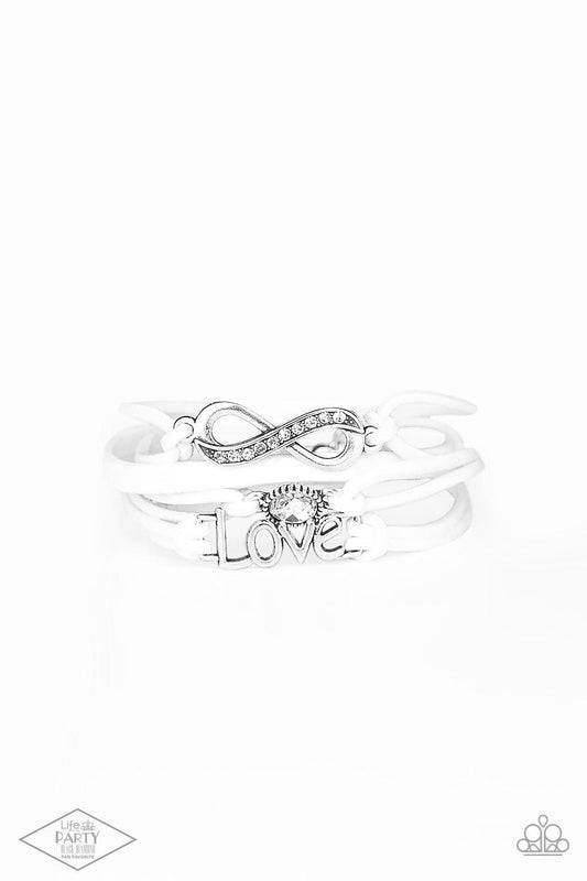 Paparazzi Accessories Infinitely Irresistible - White Strands of white suede knot around silver charms, including a glittery infinity charm, a solitaire rhinestone, and a charm whimsically spelling out “love” across the wrist. Features an adjustable clasp