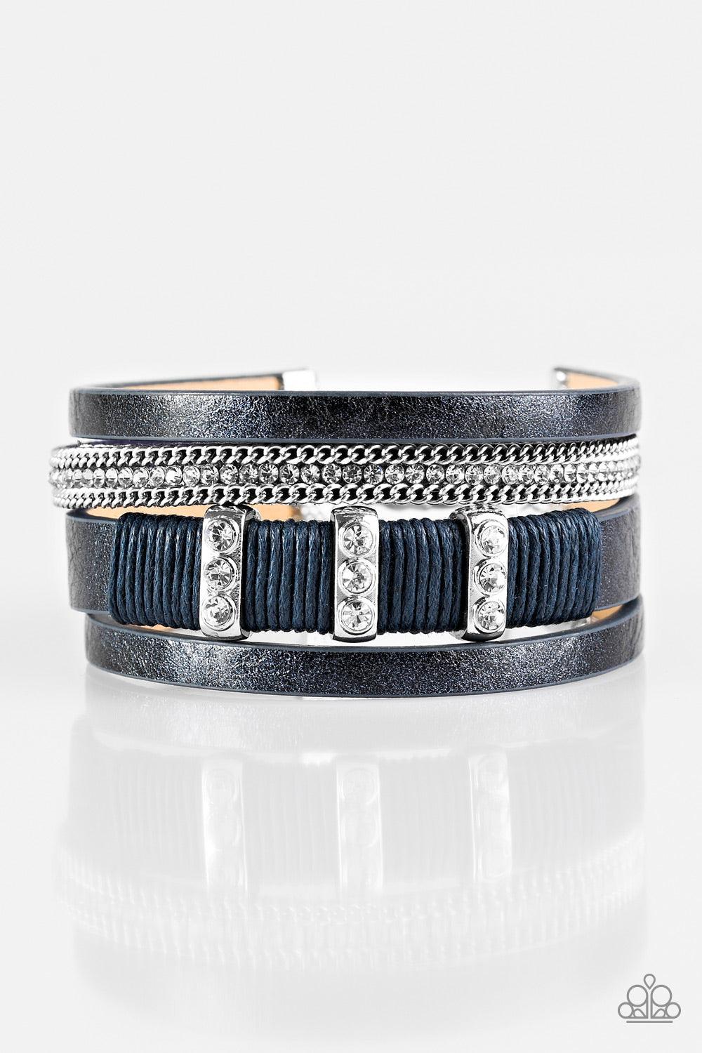Paparazzi Accessories FAME Night - Blue Metallic blue leather strands layer across the wrist. Infused with silver chain and white rhinestone accents, blue cording knots around a leather strand, securing glittery white rhinestone frames in place for a sass