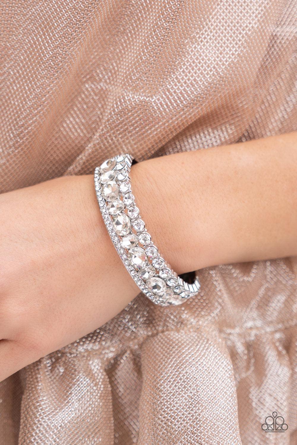 Paparazzi Accessories Mega Megawatt - White Three blinding rows of mismatched white rhinestones dramatically stack across the wrist, coalescing into a majestic bangle-like centerpiece. Features a hinged closure. Sold as one individual bracelet. Bracelets
