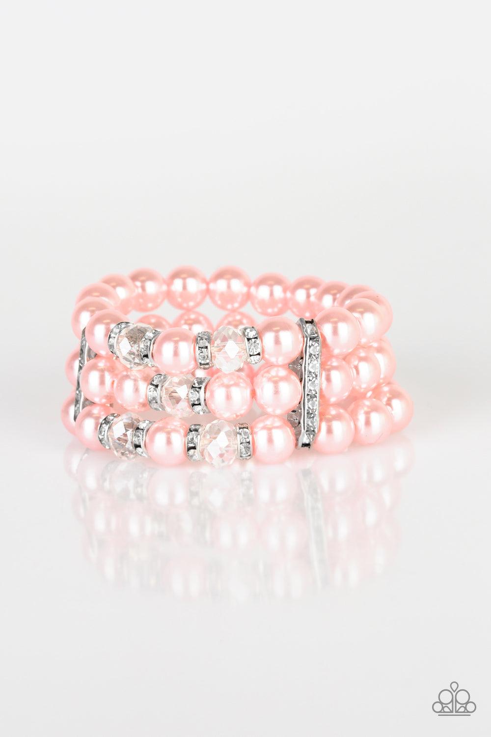 Paparazzi Accessories Undeniably Dapper - Pink Pinched between white rhinestone encrusted frames, white rhinestone encrusted rings, crystal-beads, and pink pearls are threaded along elastic stretchy bands for a glamorous look. Sold as one individual brace