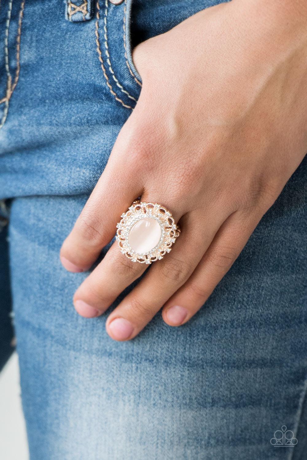 Paparazzi Accessories BAROQUE The Spell - Rose Gold Encrusted in dainty white rhinestones, a frilly rose gold frame spins around a glowing moonstone center for a regal look. Features a stretchy band for a flexible fit. Sold as one individual ring. Jewelry