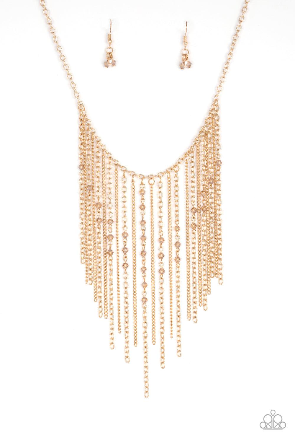 Paparazzi Accessories First Class Fringe - Gold Varying in length, mismatched gold chains stream from the bottom of a classic gold chain. Faceted golden crystal-like beads sporadically dot the free-falling chains, creating a statement-making fringe below