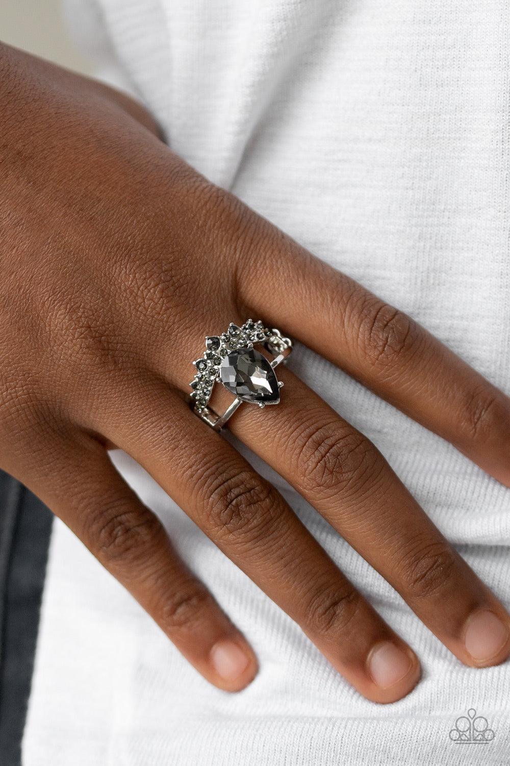 Paparazzi Accessories If The Crown Fits - Silver A shiny silver bar and smoky rhinestone encrusted bar arc across the finger, coalescing into an airy band. Featuring a regal teardrop cut, a glittery smoky rhinestone is pressed into the bands for a stateme