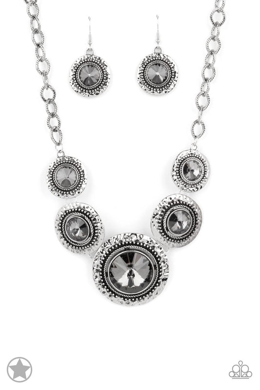 Paparazzi Accessories Global Glamour - Silver Gradually increasing in size, dramatically oversized smoky gems are pressed into the centers of hammered and silver studded frames. The blinding frames link below the collar for a glamorous, statement-making f
