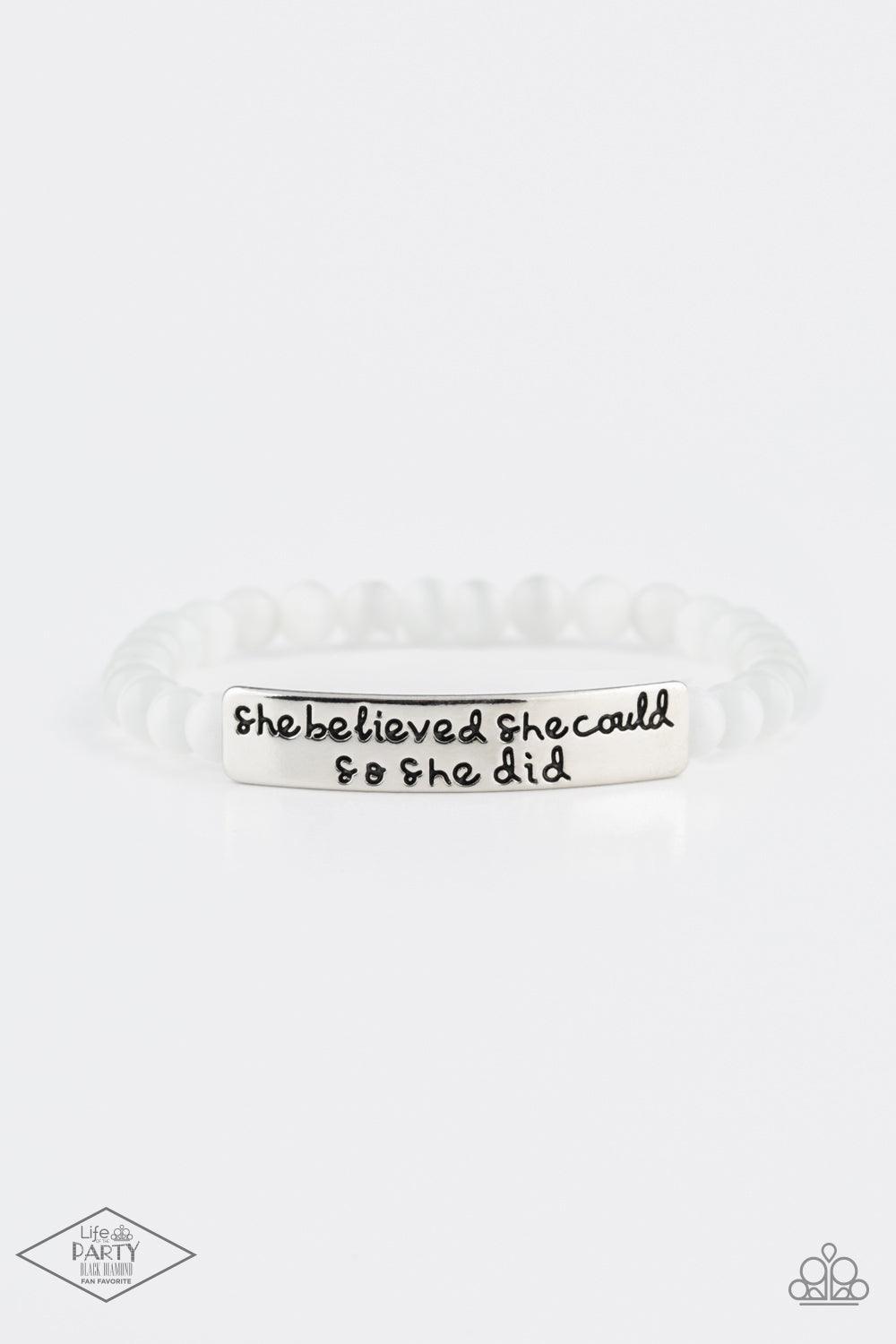 Paparazzi Accessories So She Did - White A collection of dainty white cat’s eye stone beads and an antiqued frame stamped in the inspirational phrase, “She believed she could so she did” are threaded along a stretchy band around the wrist for a whimsical