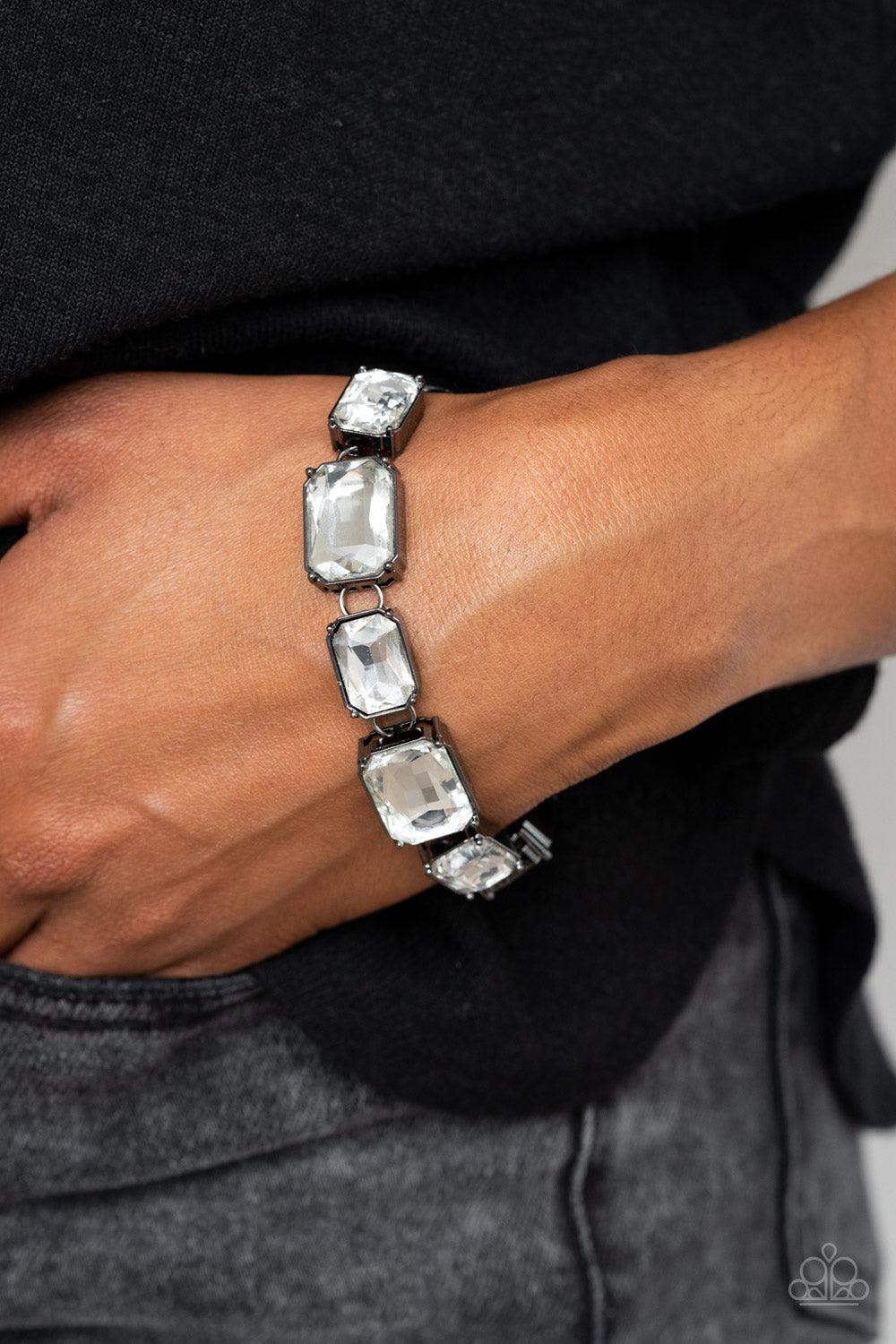 Paparazzi Accessories After Hours - Black Encased in sleek gunmetal fittings, a regal chain of small and large white emerald style gems alternate along the wrist for a timeless finish. Features an adjustable clasp closure. Sold as one individual bracelet.