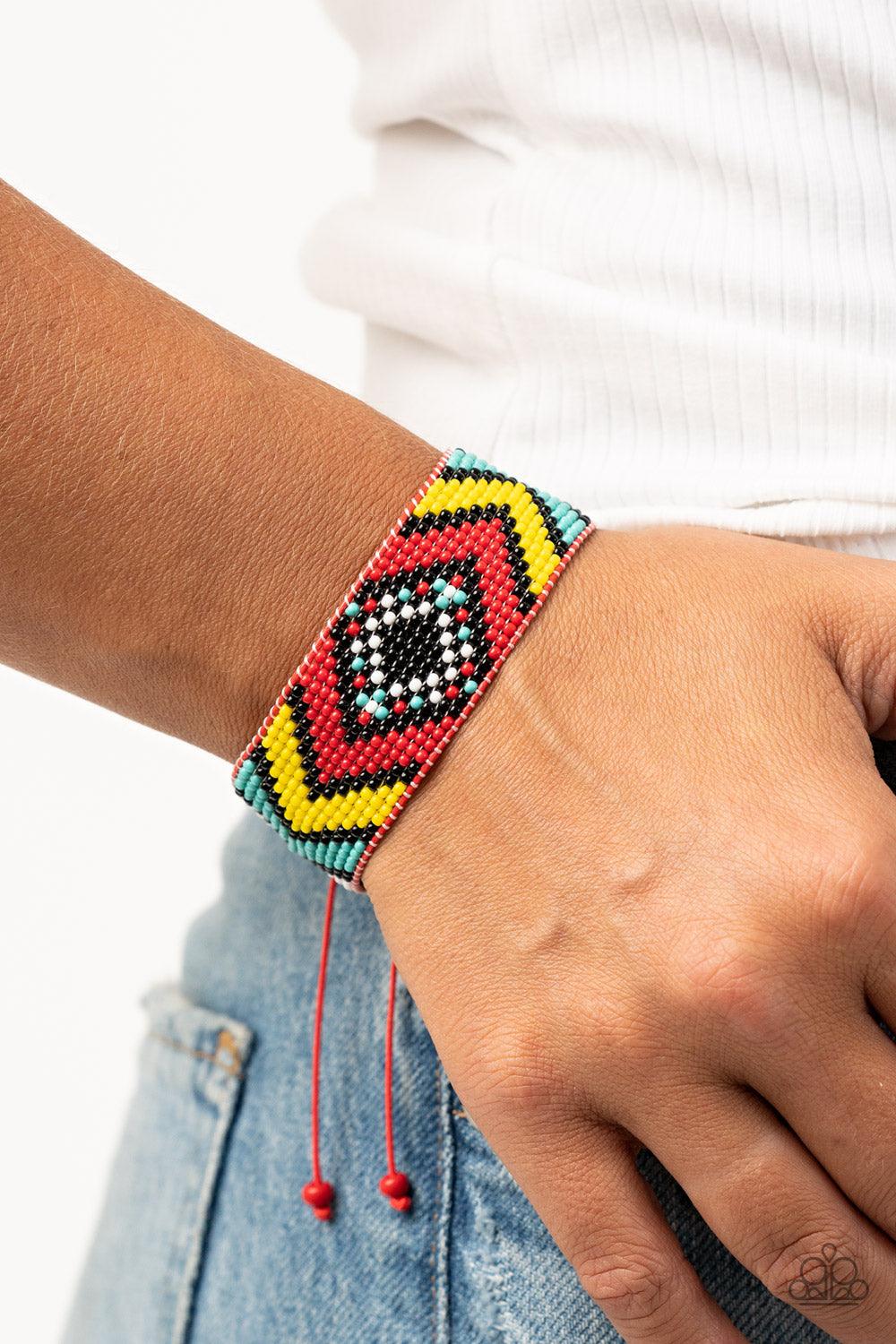 Paparazzi Accessories Desert Dive - Red A dainty collection of red, black, yellow, white, and turquoise beads are delicately weaved into a colorful textile pattern across the wrist for a southwestern inspired fashion. Features an adjustable sliding knot c