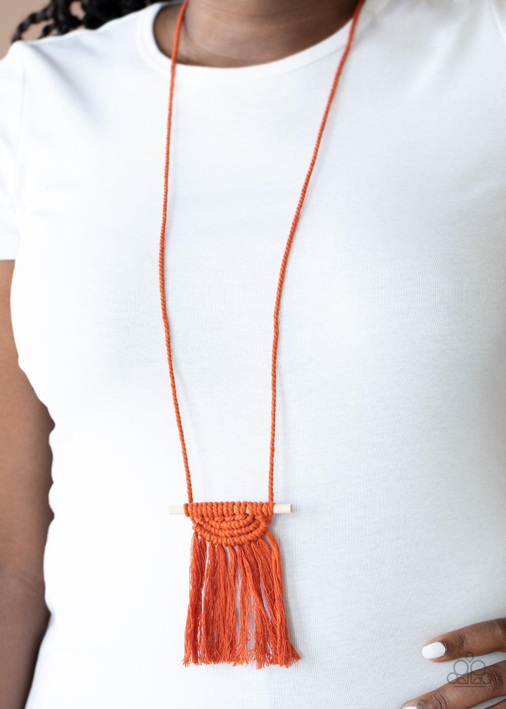 Paparazzi Accessories Between You and MACRAME - Orange Orange cording delicately wraps around a dainty wooden dowel, knotting into a tasseled macrame centerpiece at the bottom of a dramatically lengthened display. Features an adjustable sliding knot closu