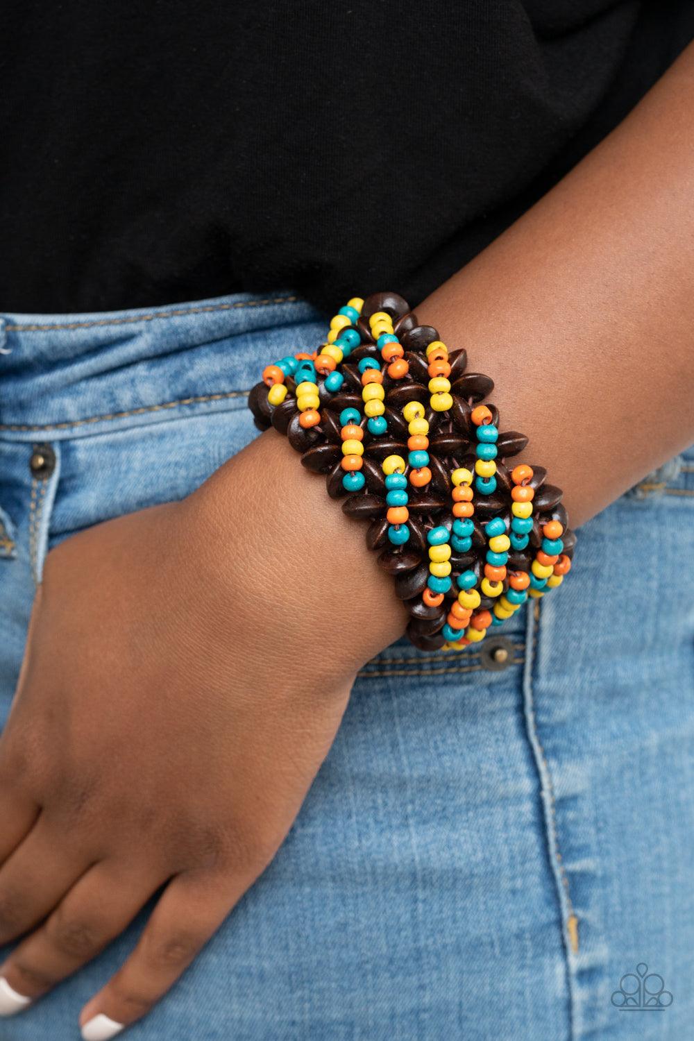 Paparazzi Accessories Cozy in Cozumel - Multi A collection of dainty blue, orange, and yellow wooden beads and brown wooden discs are threaded along knotted stretchy bands, creating a tropical floral pattern around the wrist. Sold as one individual bracel