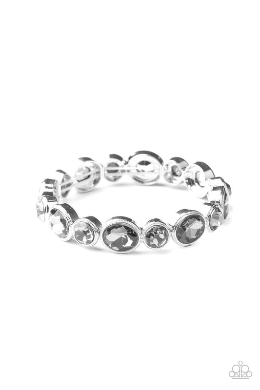 Paparazzi Accessories Still GLOWING Strong - Silver Encased in sleek silver frames, oval and round smoky rhinestones alternate along a stretchy band around the wrist for a timeless look. Sold as one individual bracelet. Get The Complete Look! Necklace: "G