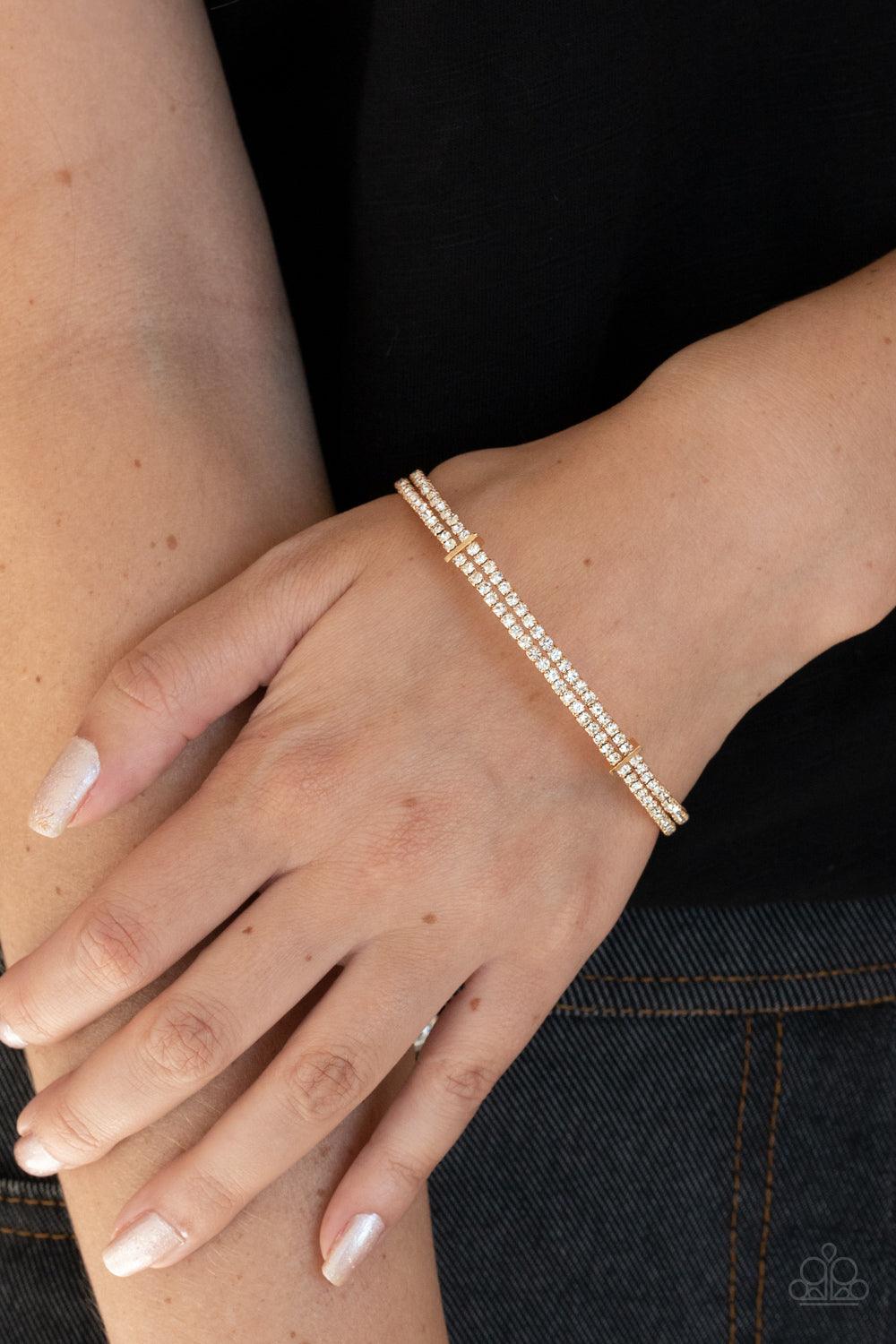 Paparazzi Accessories Standout Opulence - Gold Held together with dainty gold fittings, two glittery strands of white rhinestones delicately curl around the wrist for a timeless finish. Sold as one individual bracelet. Jewelry