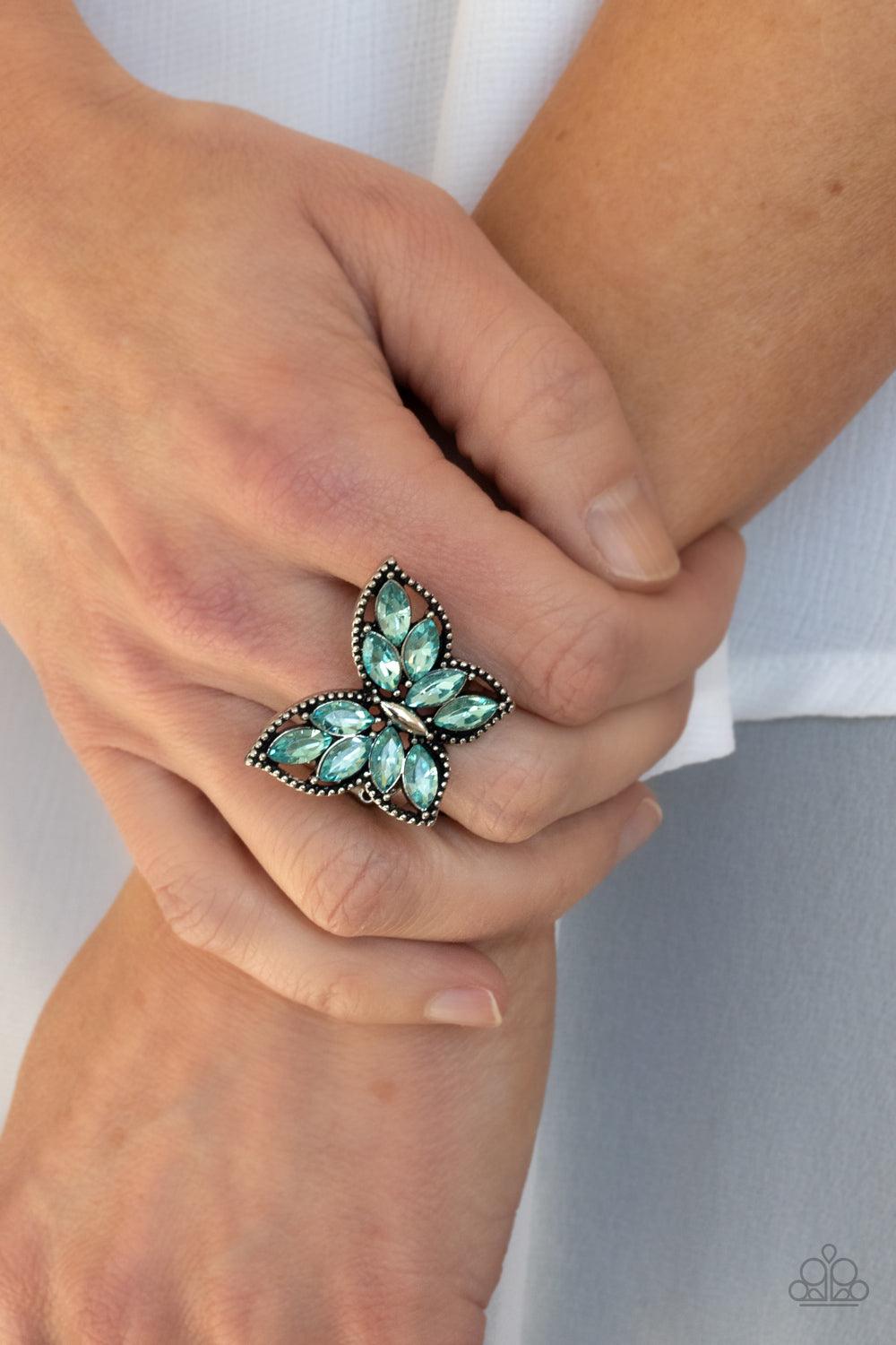 Paparazzi Accessories Fluttering Fashionista - Blue The wings of a studded silver butterfly have been adorned in glittery blue marquise rhinestones, creating a glamorous centerpiece atop the finger. Features a stretchy band for a flexible fit. Sold as one