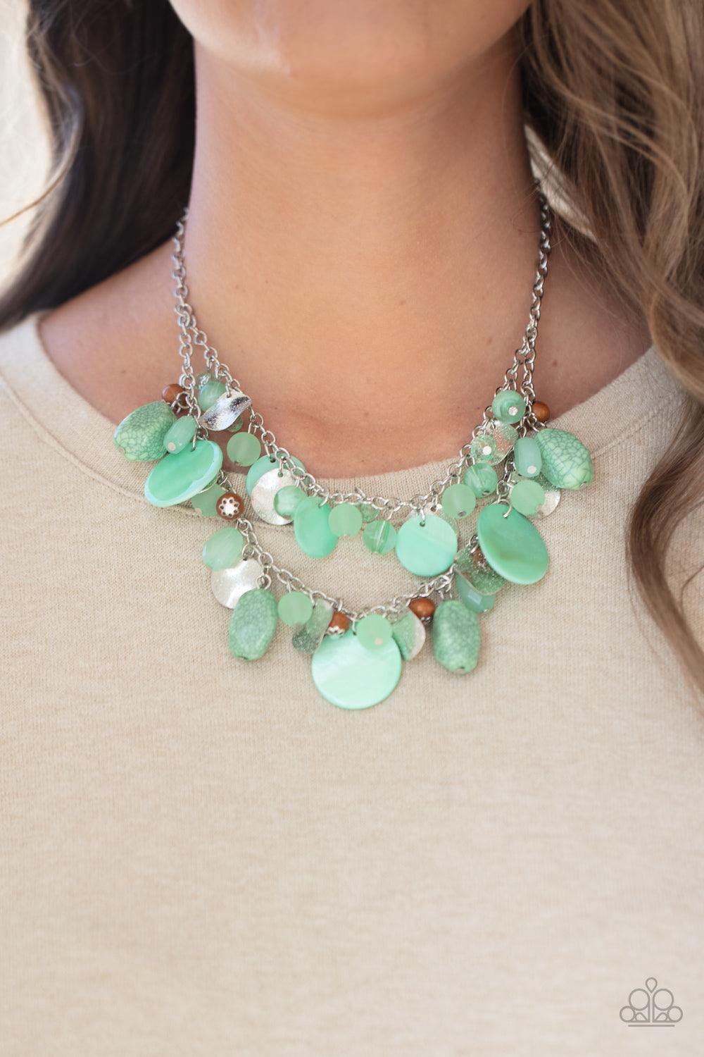 Paparazzi Accessories Spring Goddess - Green Infused with wooden beads and silver discs, an earthy collection of glassy, opaque, and shell-like Green Ash beads swing from two silver chains. The refreshing display effortlessly layers below the collar, crea
