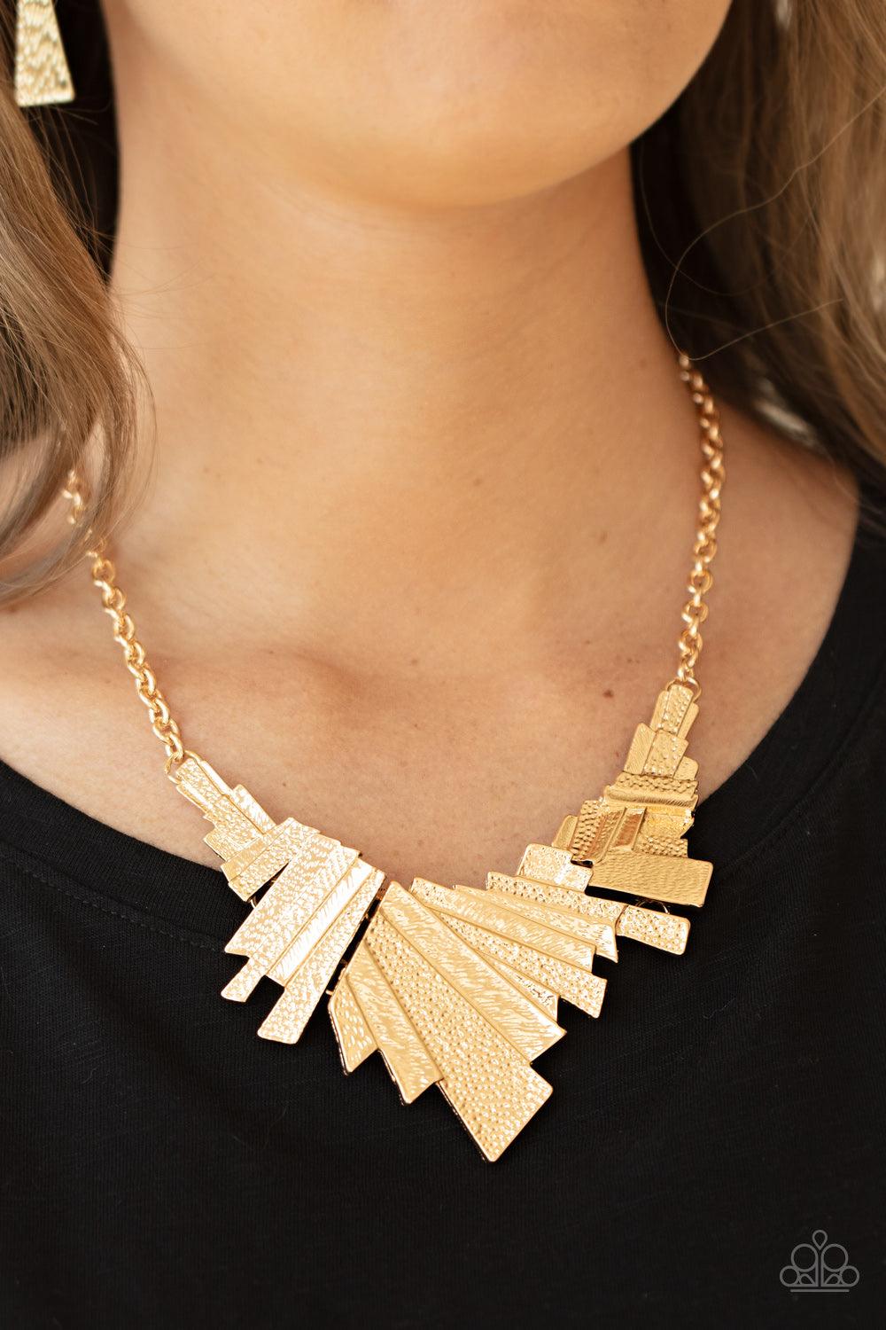 Paparazzi Accessories Happily Ever AFTERSHOCK - Gold Varying in hammered detail, a collision of rectangular gold frames connect into three shockingly shimmery plates below the collar for an intense industrial inspired look. Features an adjustable clasp cl