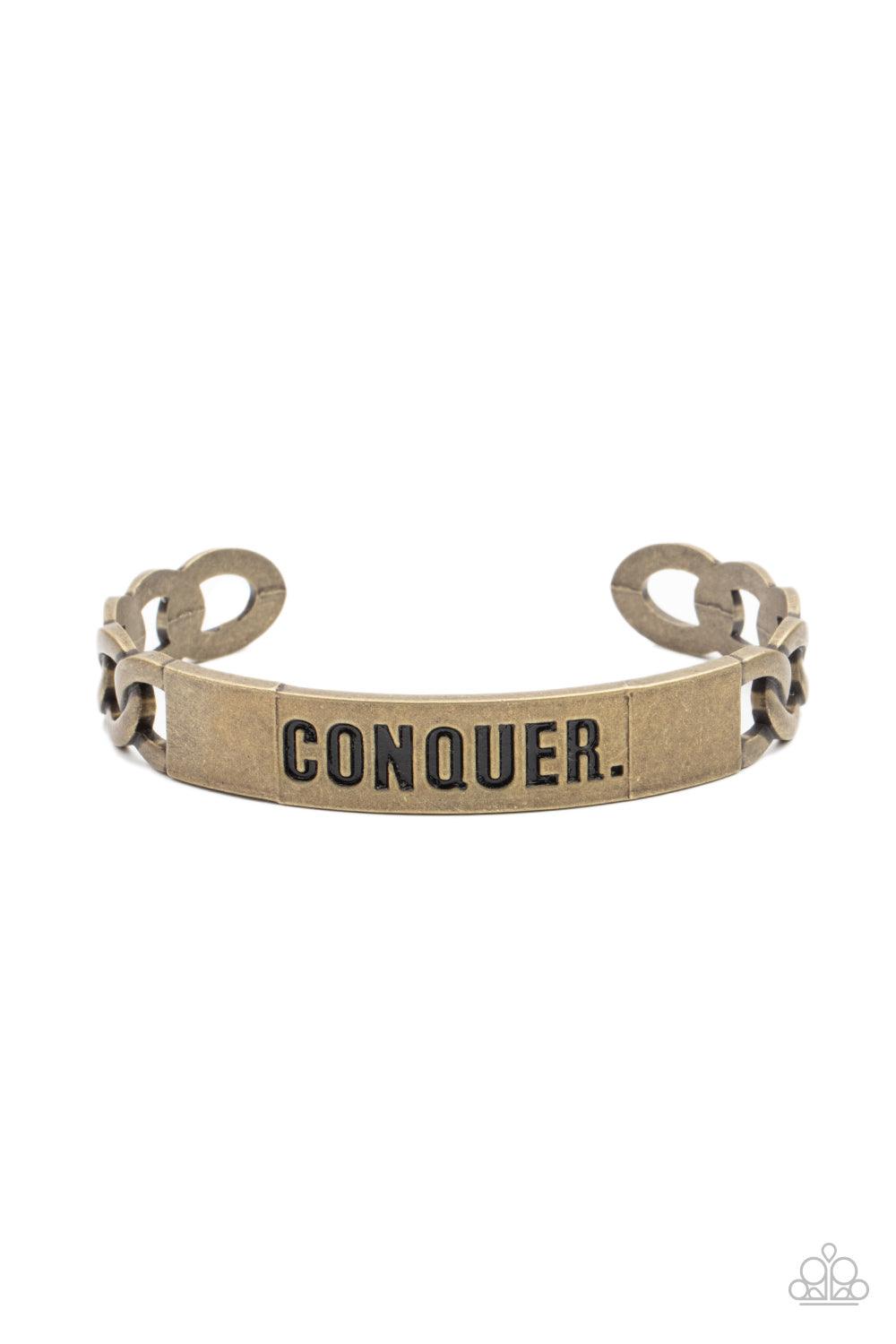 Paparazzi Accessories Conquer Your Fears - Brass Brass chain-like bars attach to a rustic brass centerpiece stamped in the powerful word, "CONQUER," creating a statement-making cuff around the wrist. Sold as one individual bracelet. Jewelry