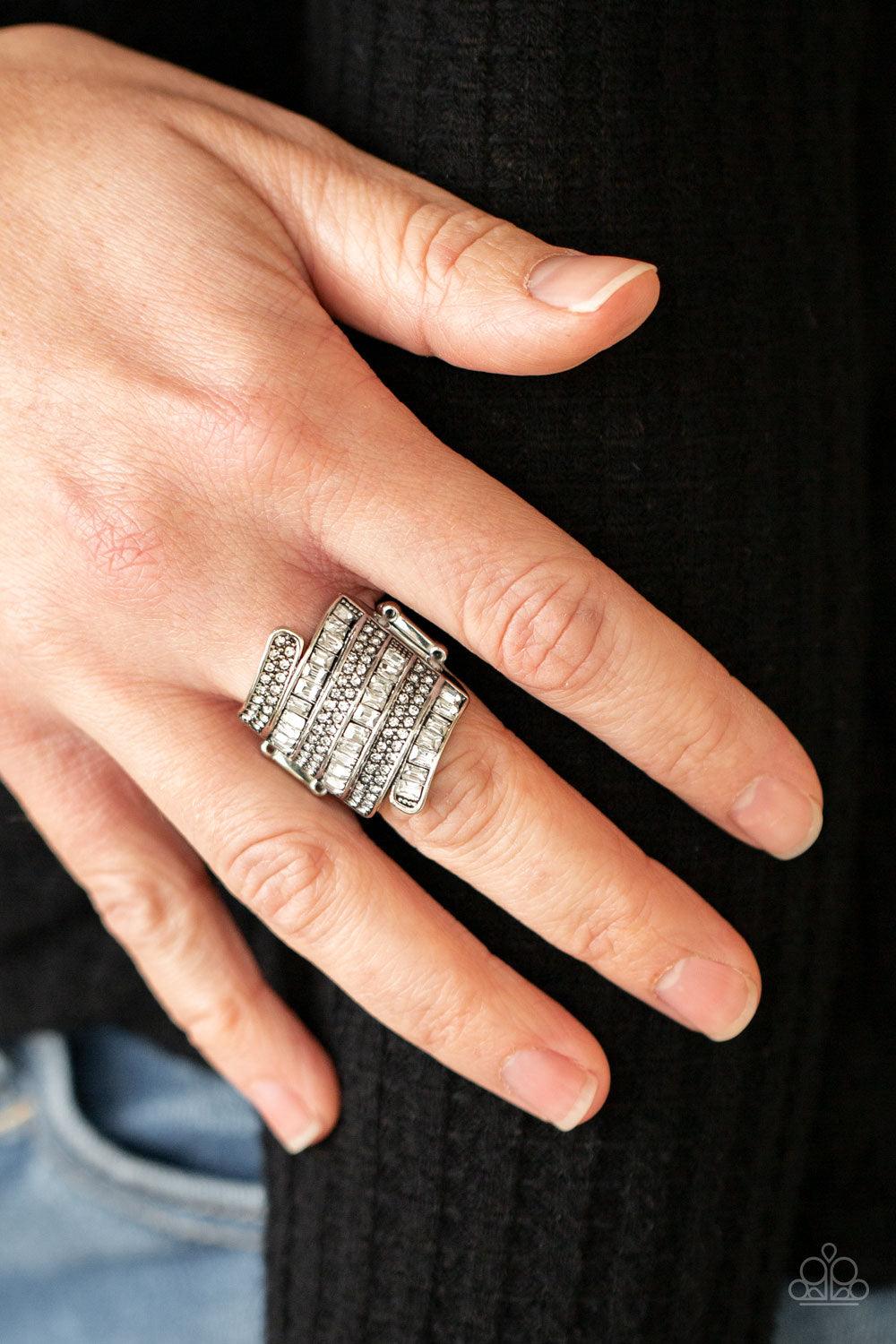 Paparazzi Accessories Hear Me UPROAR - White Dotted with pairs of dainty white rhinestones and glassy emerald cut rhinestones, stacks of silver bands wrap across the front of the finger for a jaw-dropping dazzle. Features a stretchy band for a flexible fi