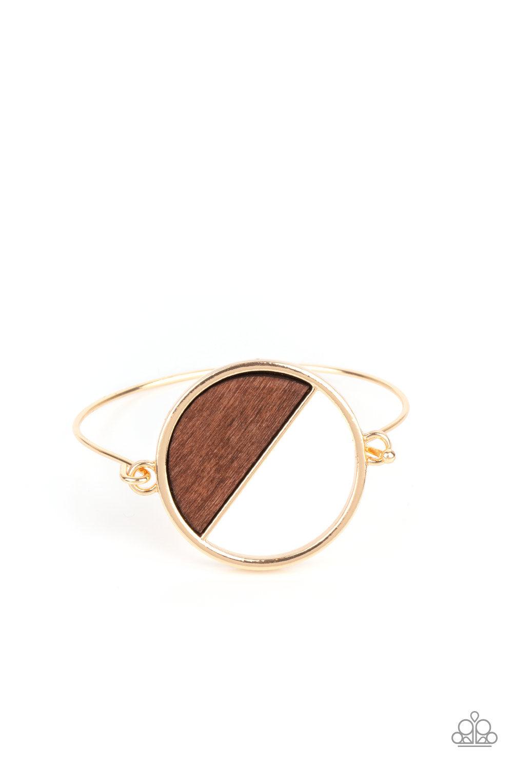 Paparazzi Accessories Timber Trade - Gold Attached to a dainty gold bar that curls around the wrist, a crescent shaped wooden accent adorns half of an airy circular centerpiece for a modern twist. Features a toggle closure. Sold as one individual bracelet