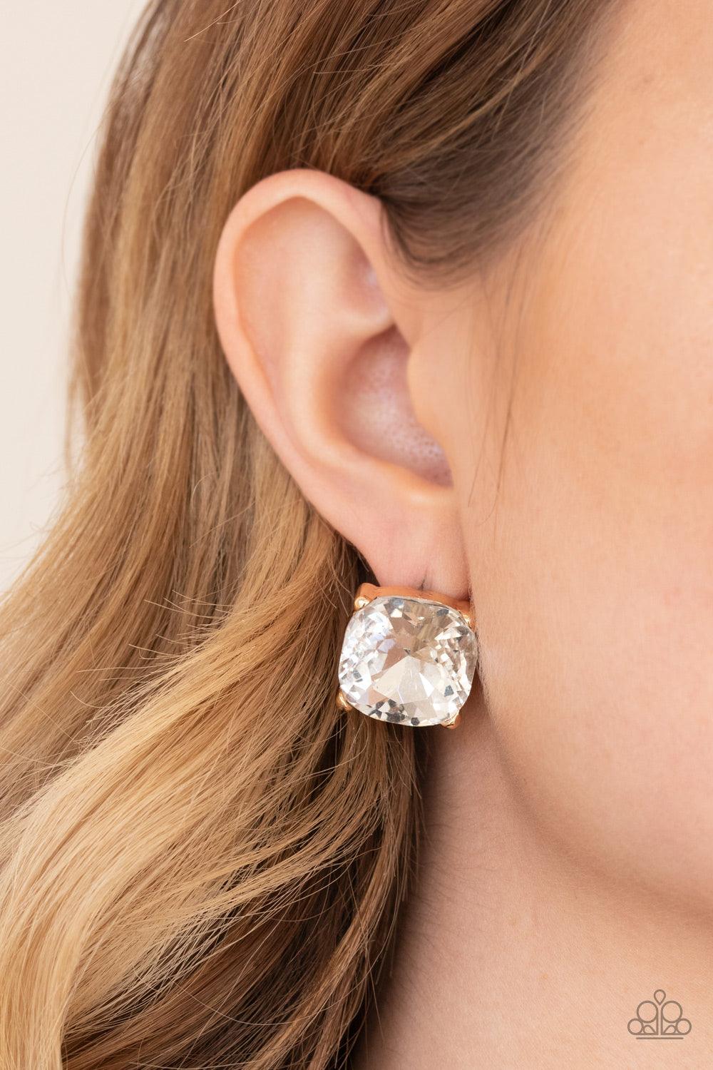 Paparazzi Accessories Royalty High - Gold A dramatically oversized white gem is nestled atop a pronged gold frame, creating a jaw-dropping dazzle. Earring attaches to a standard post fitting. Sold as one pair of post earrings. Jewelry