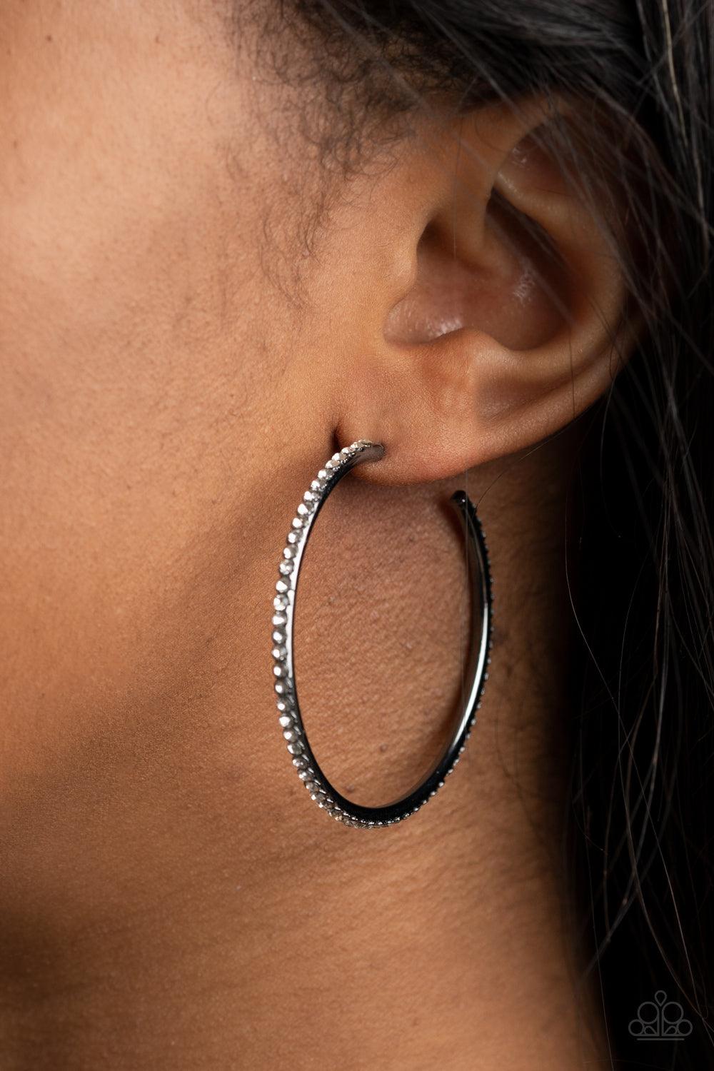 Paparazzi Accessories By Popular Vote - Black The spine of a gunmetal hoop is encrusted in dainty white rhinestones, creating wraparound shimmer. Earring attaches to a standard post fitting. Hoop measures approximately 1 3/4" in diameter. Sold as one pair