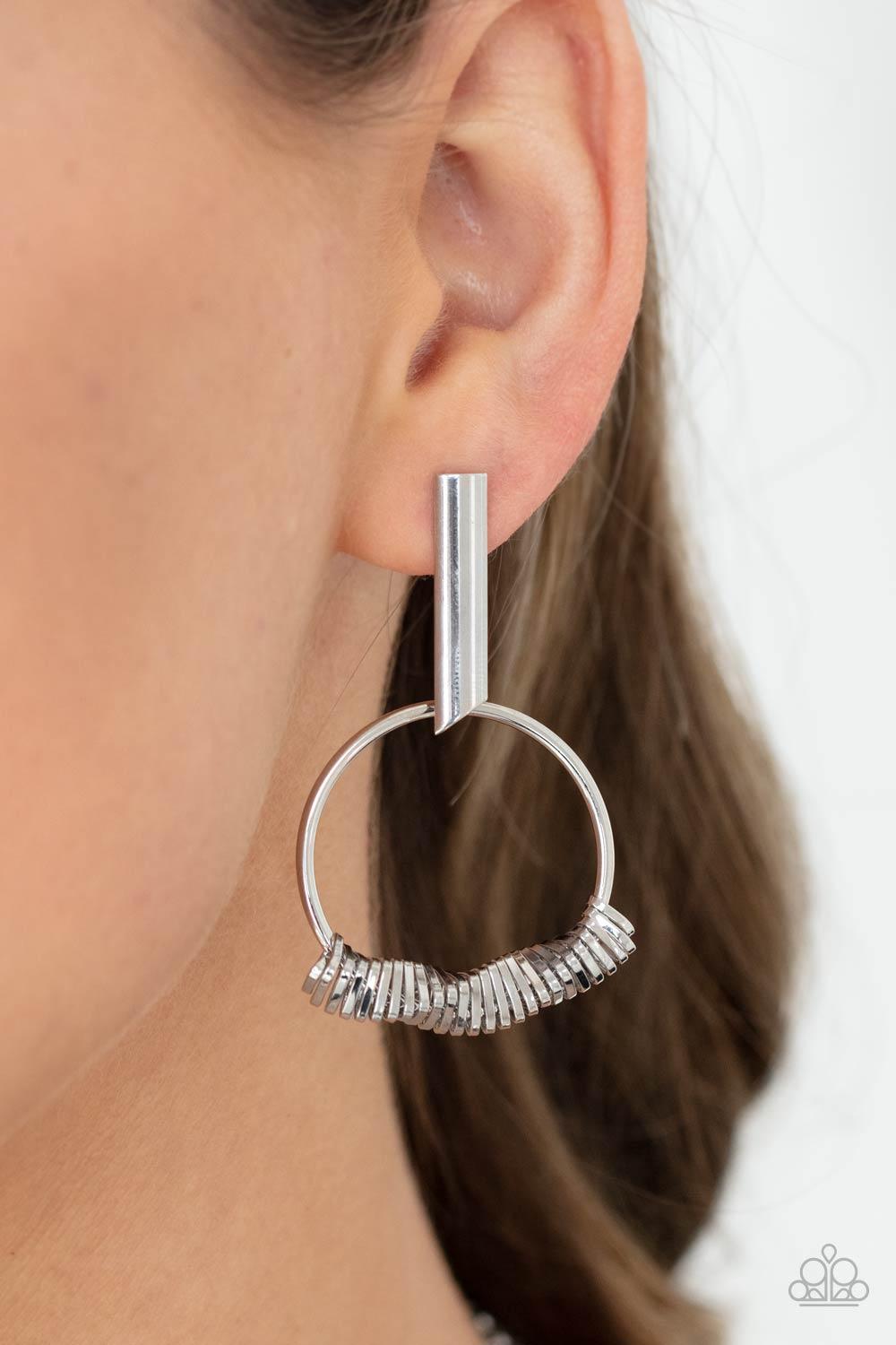 Paparazzi Accessories Set Into Motion - Silver Glistening silver triangular rings are delicately fitted in place along the bottom of a dainty silver hoop, creating the illusion of twisting movement. The edgy hoop links to a silver rectangular hoop, creati