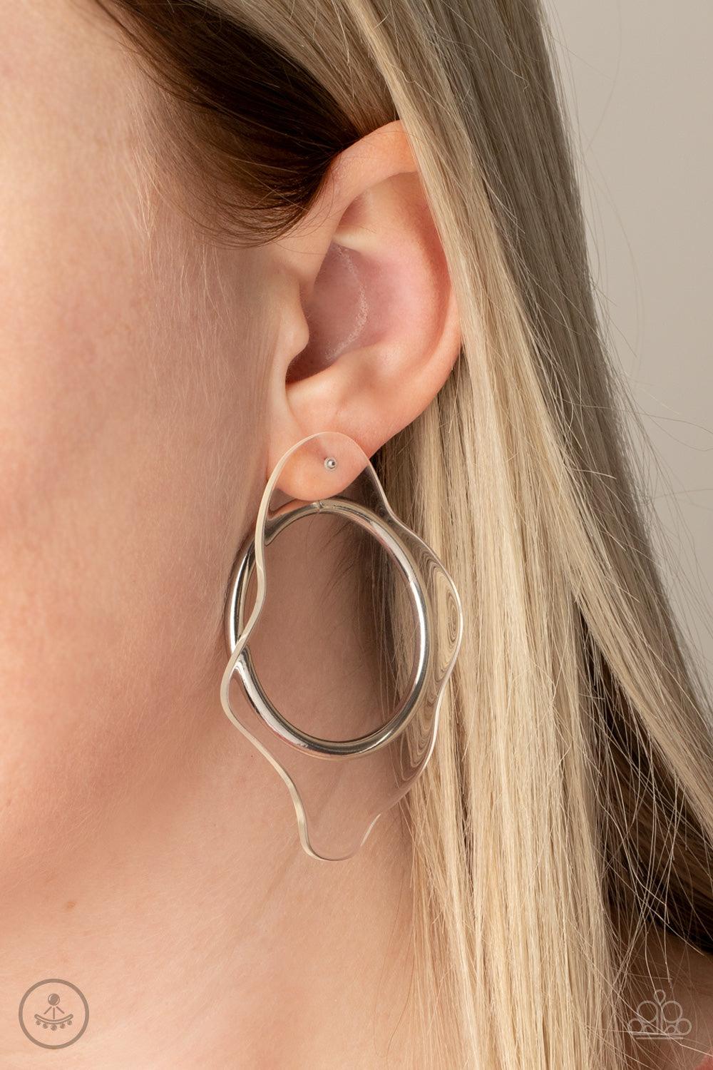 Paparazzi Accessories Clear The Way! - White A warped piece of clear acrylic attaches to a double-sided post, while an oversized silver hoop peeks out beneath the ear for a bold look. Earring attaches to a standard post fitting. Sold as one pair of double