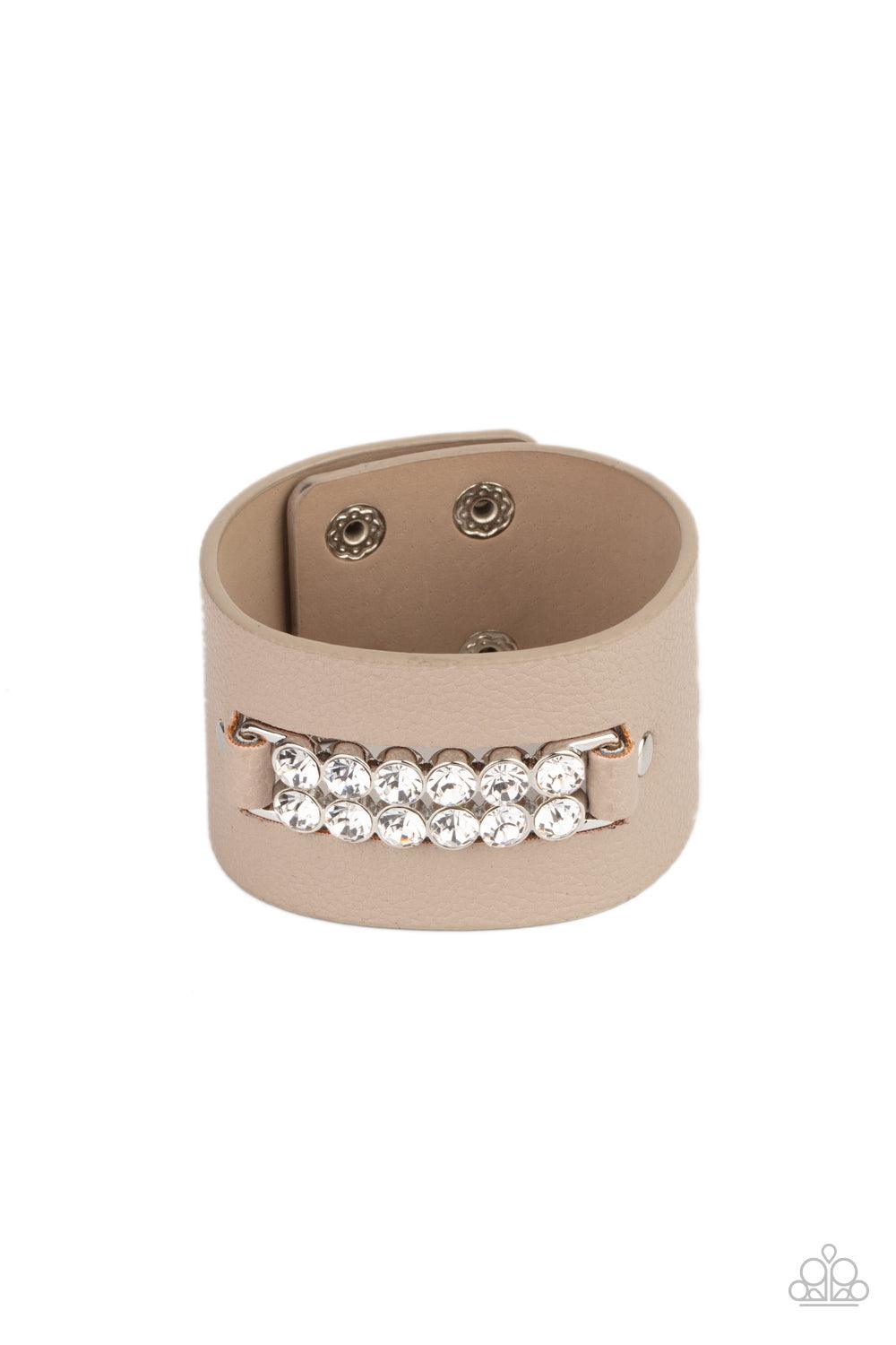 Paparazzi Accessories Runway Rebellion - Brown Two rows of oversized white rhinestones are studded in place across the center of a thick leather band, creating a sassy centerpiece around the wrist. Features an adjustable snap closure. Sold as one individu