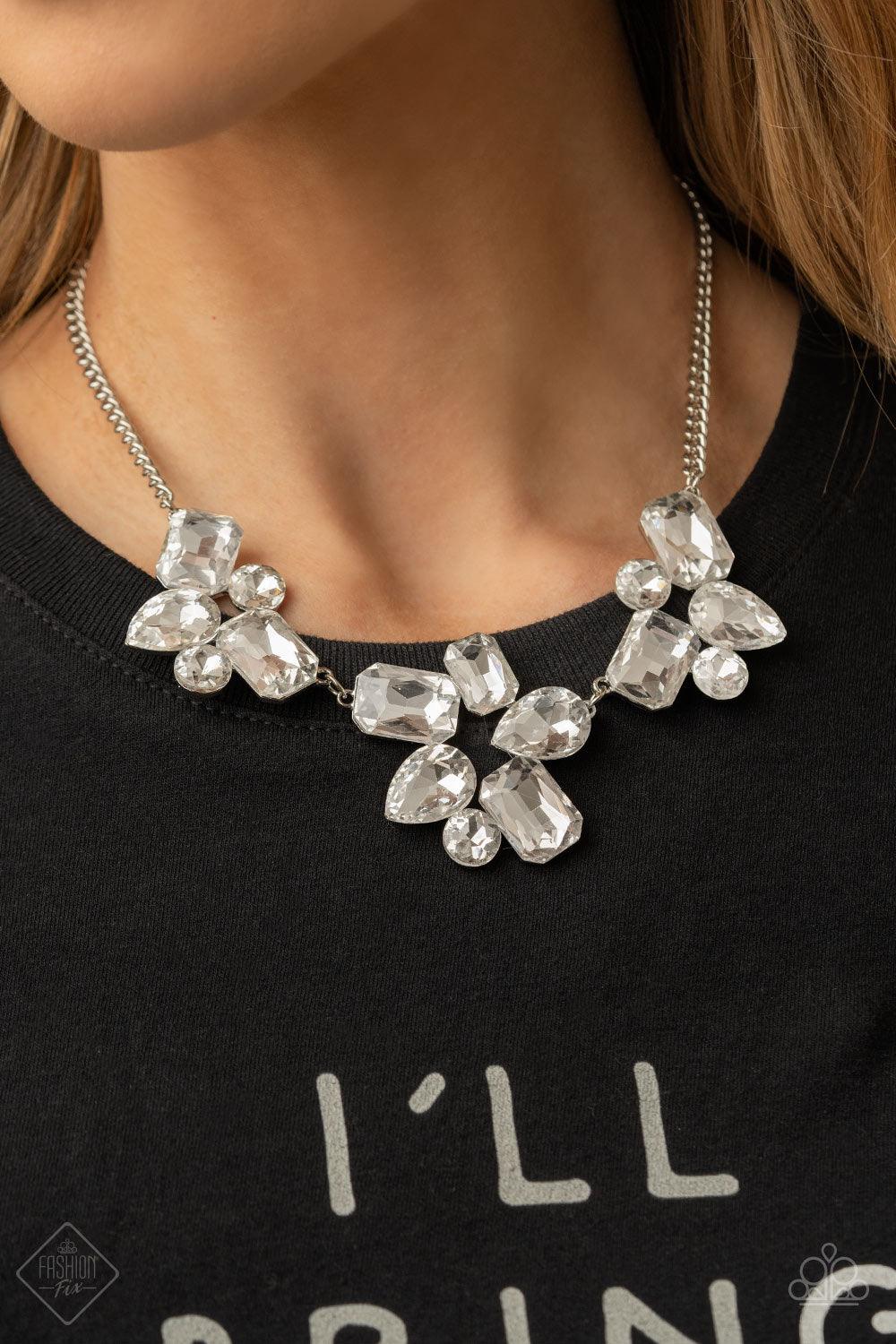 Paparazzi Accessories Galactic Goddess - White An unexpected explosion of oversized round, teardrop, and emerald cut rhinestones cluster into haphazard groupings. The blinding clusters link together, creating a stellar statement piece that sits below the