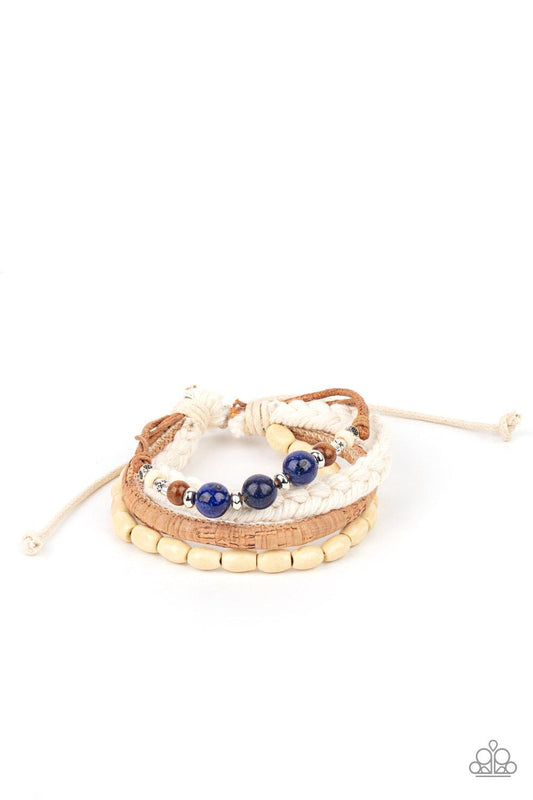 Paparazzi Accessories Natural-Born Navigator - Blue Featuring cork, thread, and wood, mismatched metallic accents, glassy blue stones, and wood beads adorn earthy layers around the wrist for a whimsical look. Features an adjustable sliding knot closure. S
