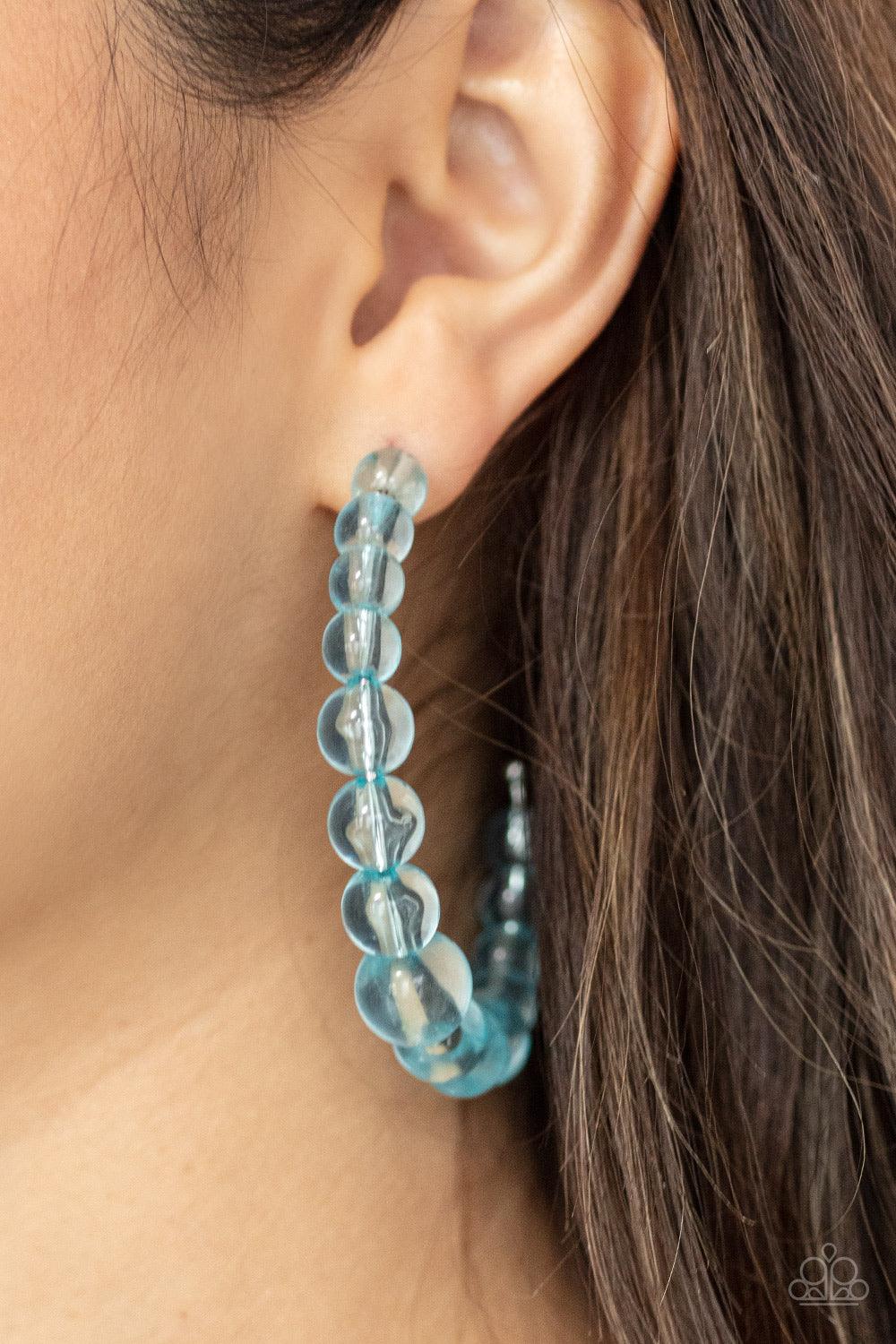 Paparazzi Accessories In The Clear - Blue Gradually increasing in size at the center, a glassy collection of Cerulean beads are threaded along an oversized hoop for a bubbly effect. Earring attaches to a standard post fitting. Hoop measures approximately