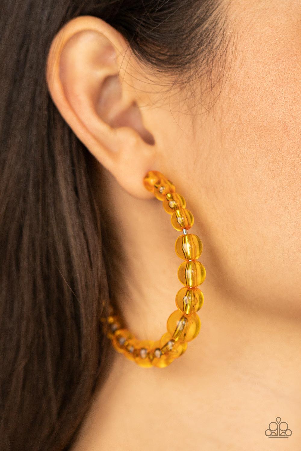 Paparazzi Accessories In The Clear - Orange Gradually increasing in size at the center, a glassy collection of Marigold beads are threaded along an oversized hoop for a bubbly effect. Earring attaches to a stand post fitting. Hoop measures approximately 2