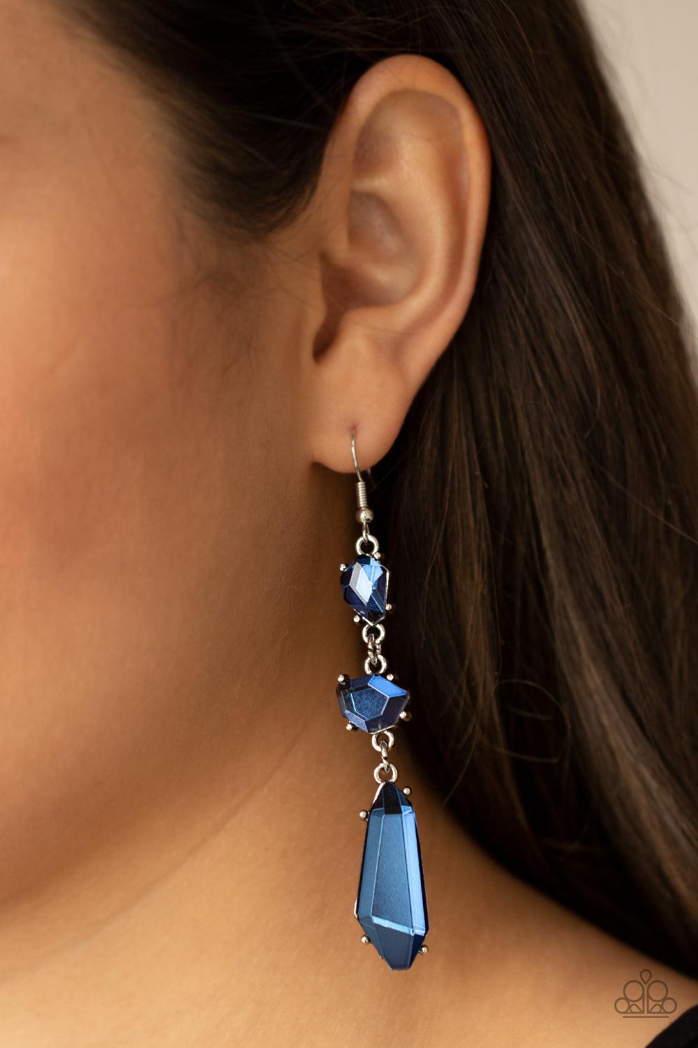 Paparazzi Accessories Sophisticated Smolder - Blue Featuring raw cuts, an asymmetrical collection of faceted blue gems trickles from the ear, creating a smoldering chandelier. Earring attaches to a standard fishhook fitting. Sold as one pair of earrings.