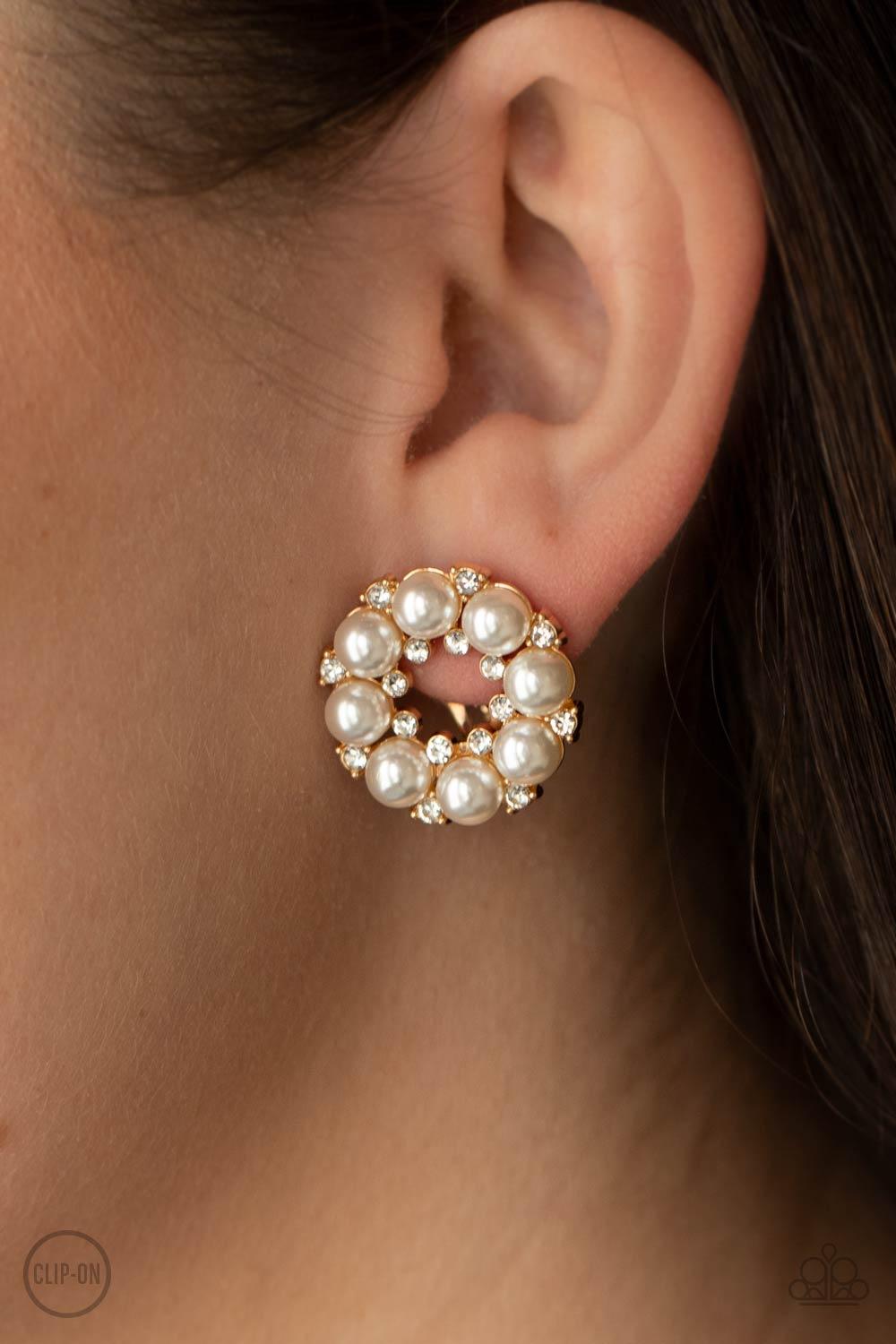 Paparazzi Accessories Roundabout Ritz - Gold *Clip-On A timeless collection of dainty white rhinestones and classic white rhinestones spin into a bubbly hoop. Earring attaches to a standard clip-on fitting. Sold as one pair of clip-on earrings. Jewelry