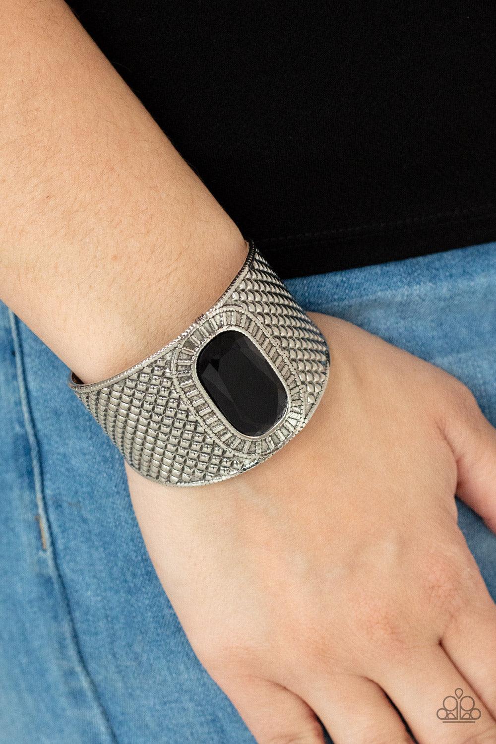 Paparazzi Accessories Poshly Pharaoh - Black An ovsized black gem is pressed into the center of a thick silver cuff embossed in diamond-like textures, creating a bold tribal inspired centerpiece around the wrist. Sold as one individual bracelet. Jewelry