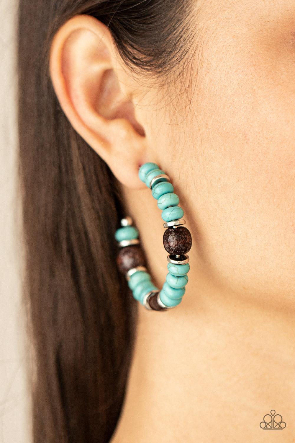 Paparazzi Accessories Definitely Down-To-Earth - Blue An earthy collection of turquoise stone beads, silver discs, and brown wooden beads are delicately threaded along a dainty wire, creating an artisan inspired hoop. Earring attaches to a standard post f