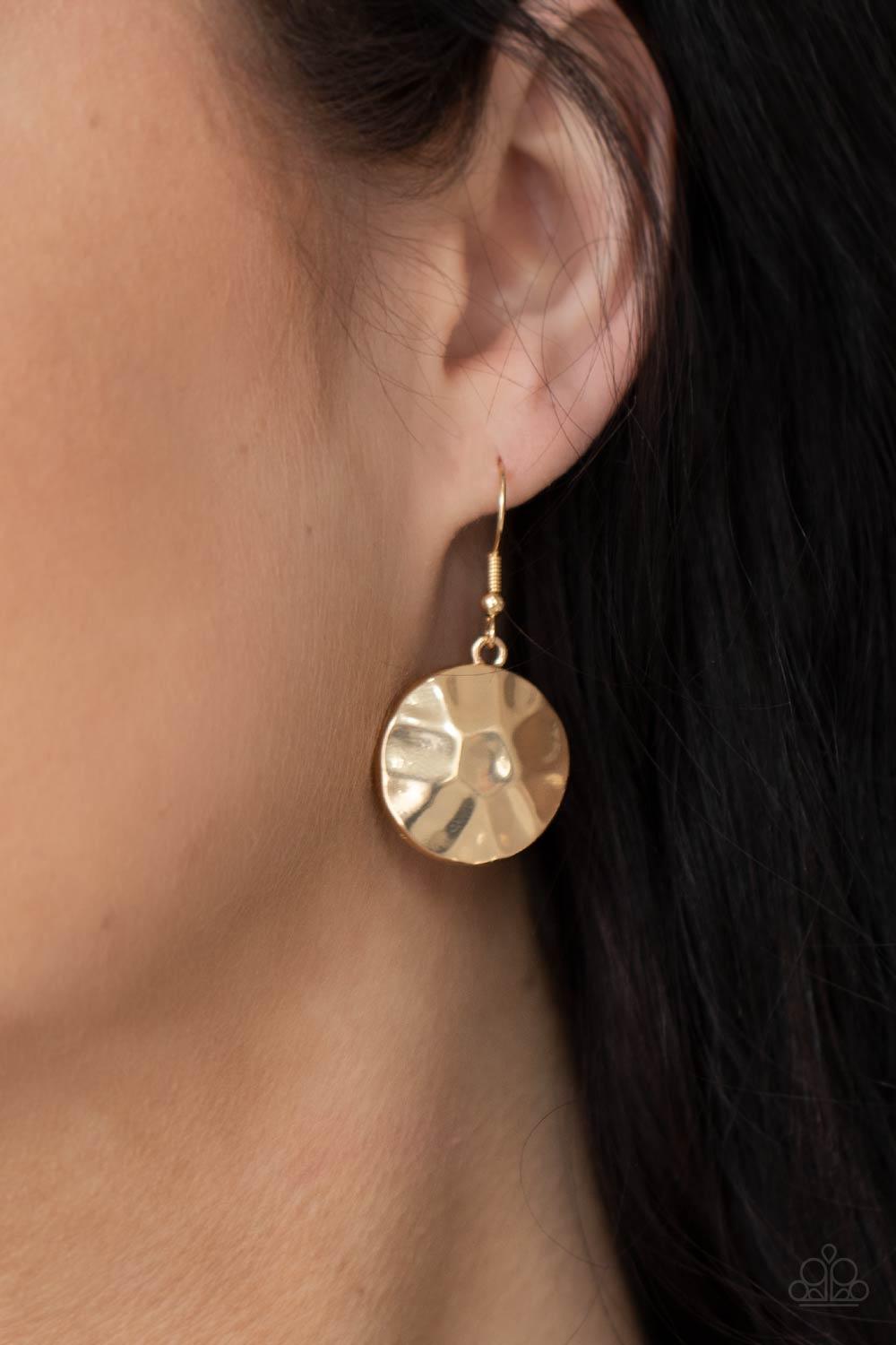 Paparazzi Accessories Token Treasure - Gold Featuring a hammered finish, a collection of glistening gold discs delicately connect into a netted pendant at the bottom of knotted black cords for a statement-making look. Features an adjustable clasp closure.