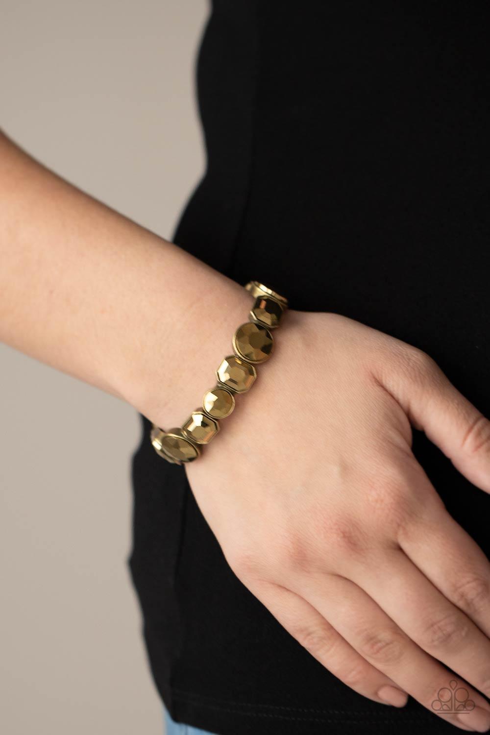 Paparazzi Accessories Extra Exposure - Brass Encased in sleek brass frames, a smoldering collection of round and emerald cut aurum rhinestones glide along stretchy bands around the wrist, creating a sparkly industrial statement piece. Sold as one individu