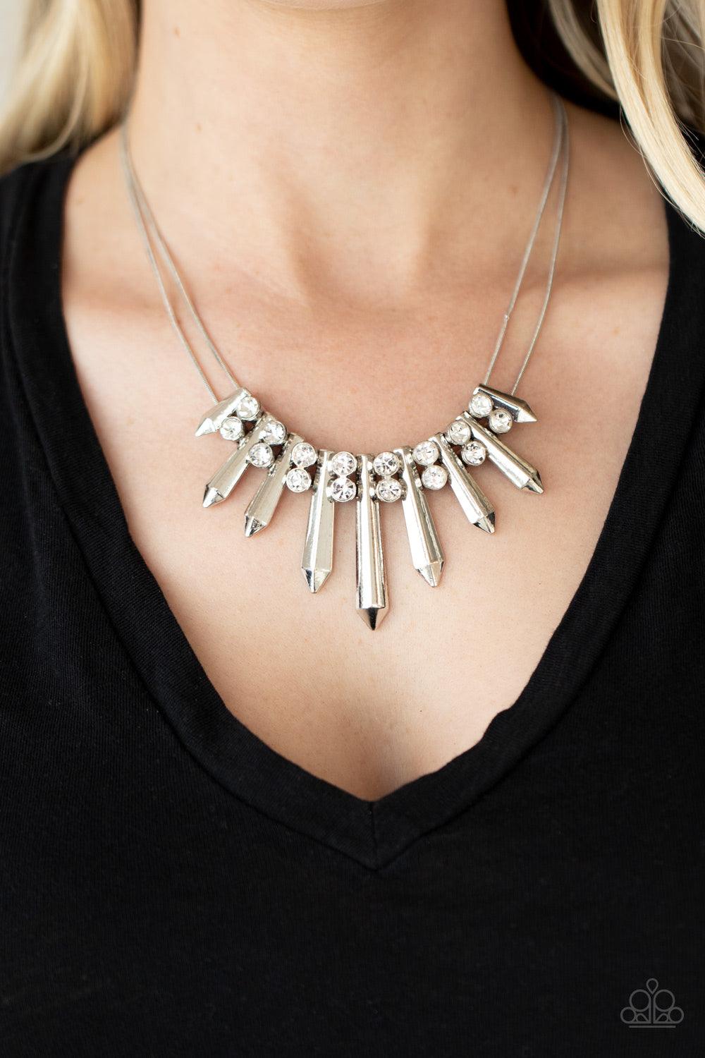 Paparazzi Accessories Dangerous Dazzle - White Pairs of glittery white rhinestones alternate between flared silver rods that are threaded along two rows of flat silver chains, creating a dangerous fringe below the collar. Features an adjustable clasp clos