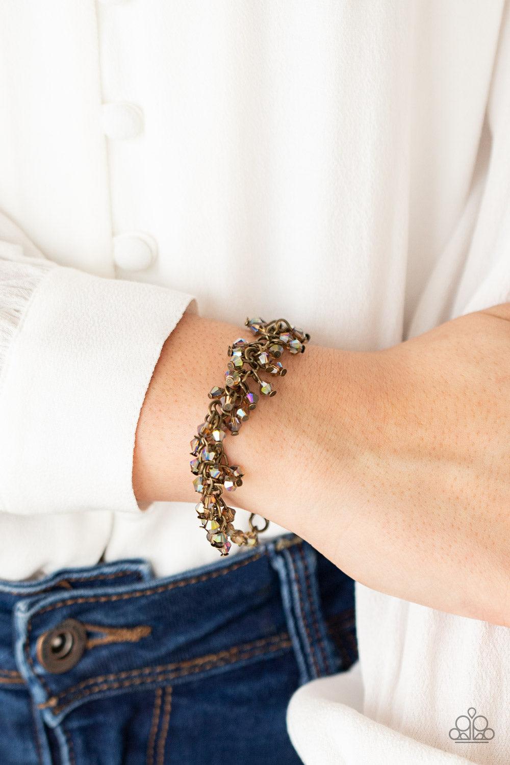 Paparazzi Accessories Twinkly Twilight - Brass Dainty brassy tone-on-tone iridescent beads swing from a classic brass chain, creating a clustered fringe around the wrist. Features an adjustable clasp closure. Sold as one individual bracelet. Get The Compl